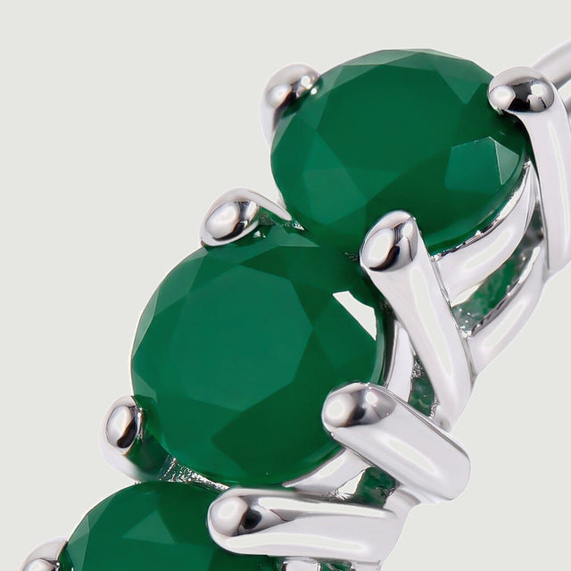 Round green gemstone facets and bright silver colored prongs fill this close view.