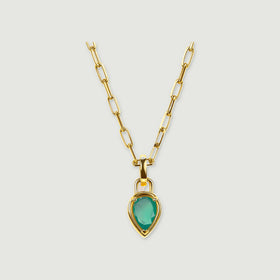 A yellow gold plated necklace with elongated links and a pear-shaped green pendant is centered on a pale gray background.