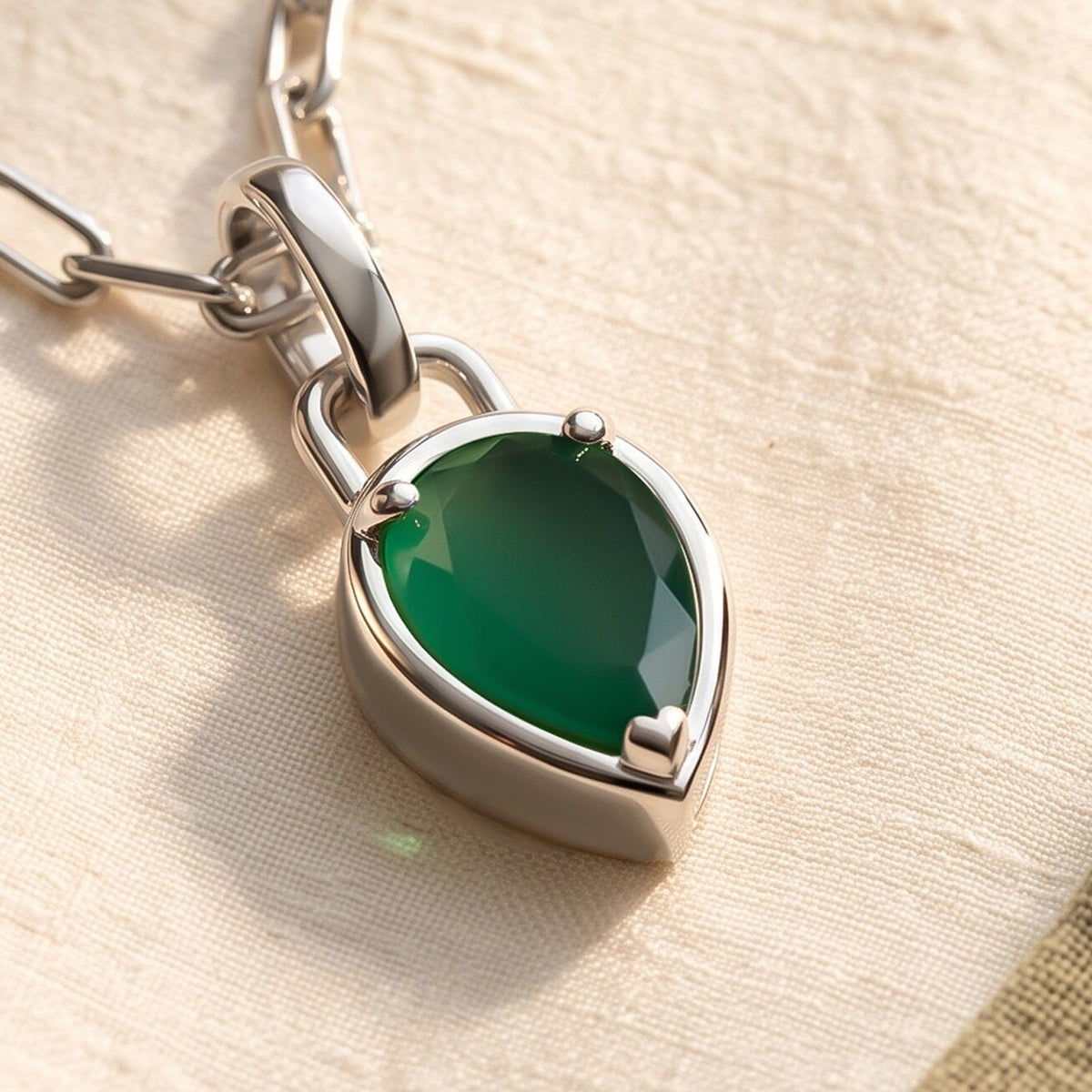 An angled close view reveals the raised white rhodium plated setting and side wall beneath the green pear-shaped stone.