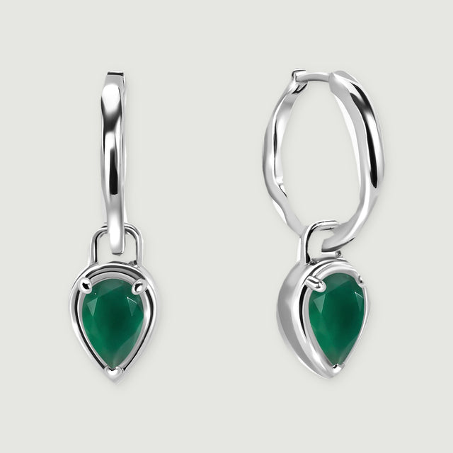 Two white rhodium plated hoop earrings carry faceted green pear drops against a light gray background.