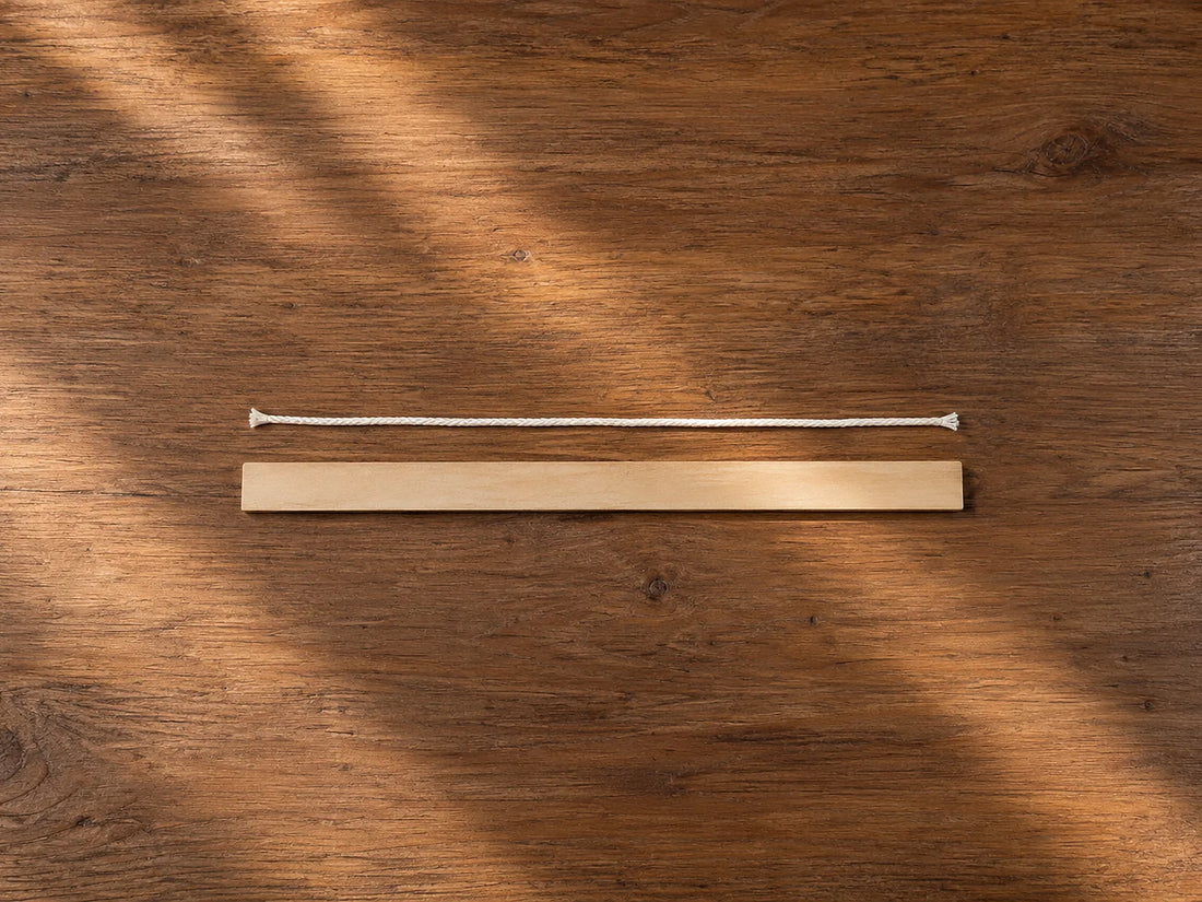Natural window light illuminates one unjoined silk cord laid straight beside an unmarked ruler.