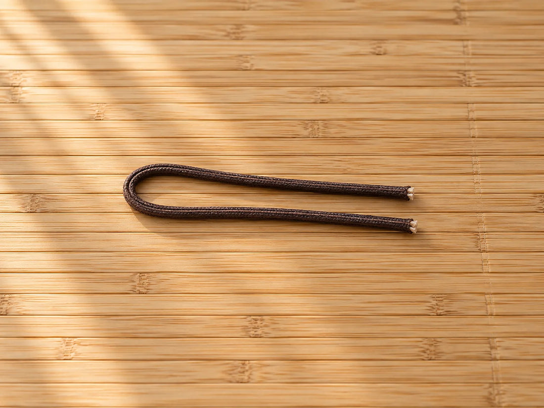 Natural window light illuminates one unfinished cord folded once into two parallel lengths with both cut ends visible.