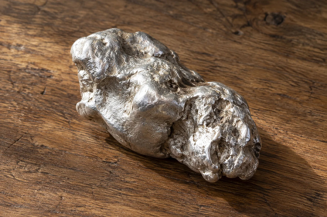 Natural window light illuminates one rough white-silver casting nodule without any hallmark.