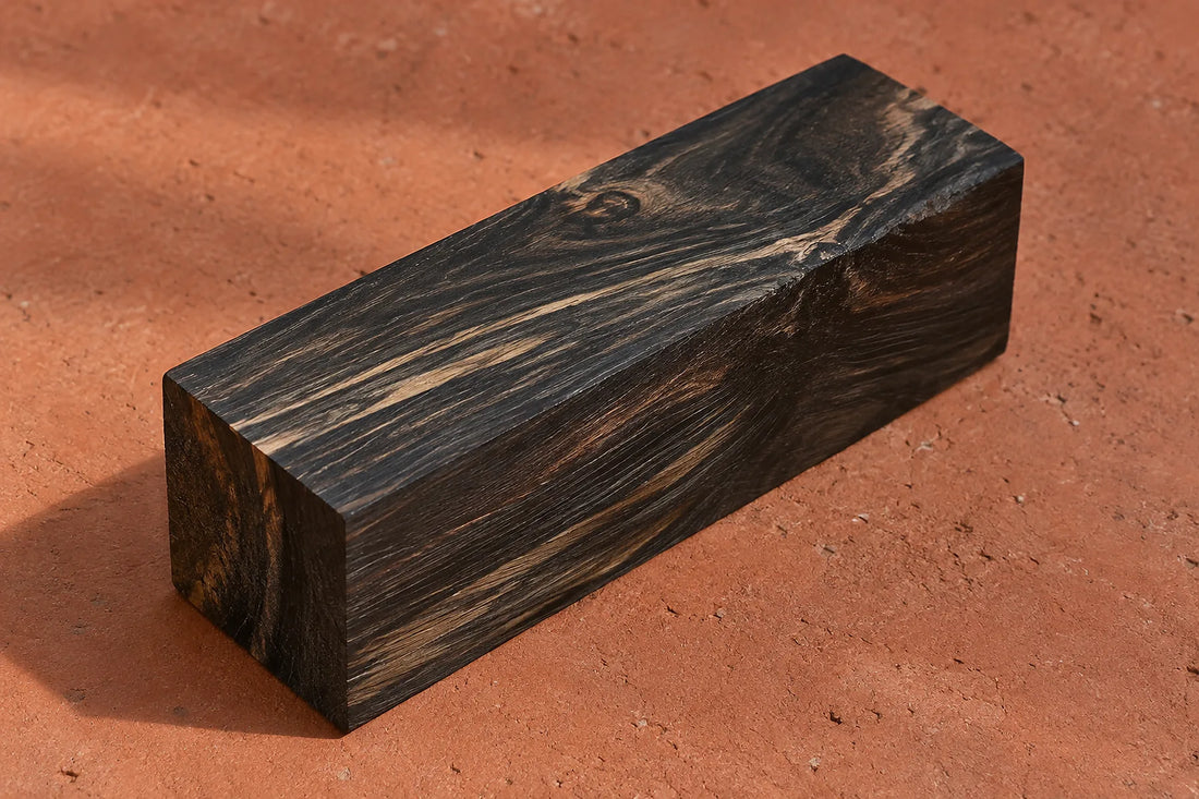 Natural window light illuminates one dark ebony offcut showing dense wood grain.