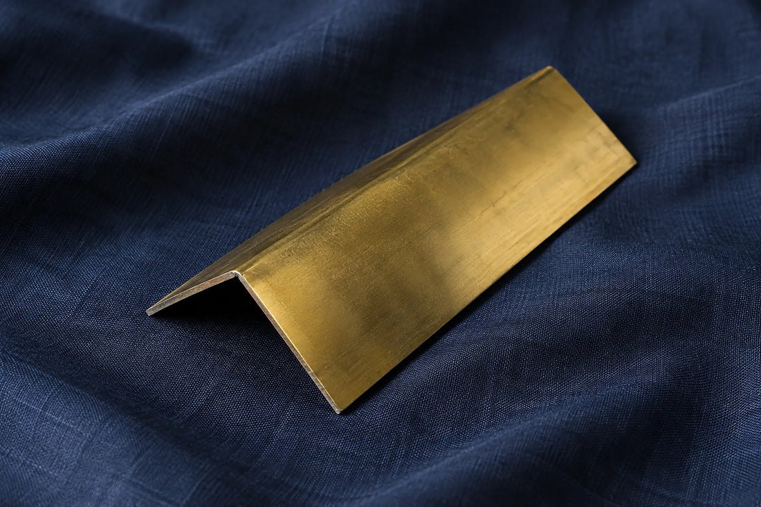 Natural window light illuminates one folded yellow brass sheet offcut with a clean raw edge.