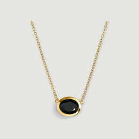 A yellow-gold-plated chain holds a faceted oval black obsidian pendant against a light grey background.
