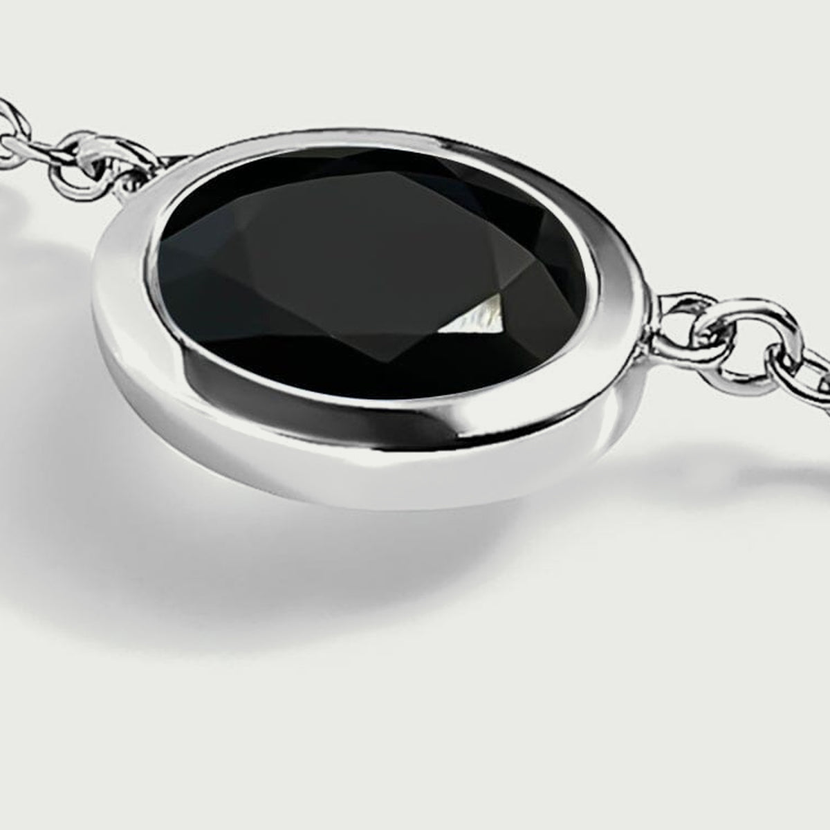 A side view shows the white-rhodium-plated rim and the chain links beside the oval black stone.