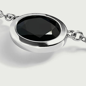 A side view shows the white-rhodium-plated rim and the chain links beside the oval black stone.