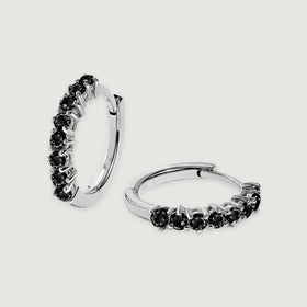 A pair of white rhodium plated hoops shows black stones and hinged closures on light gray.