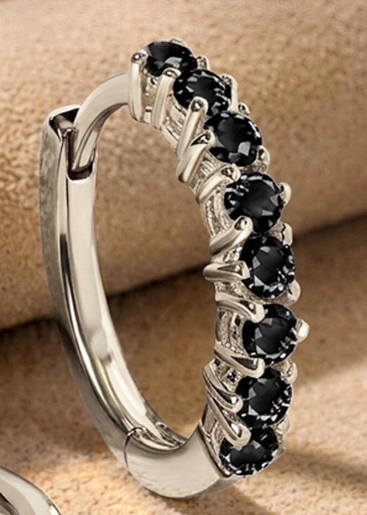 Faceted black stones and polished white rhodium plated prongs fill a close view of the upright earring.