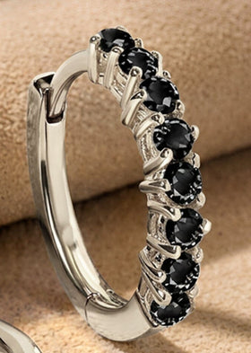 Faceted black stones and polished white rhodium plated prongs fill a close view of the upright earring.
