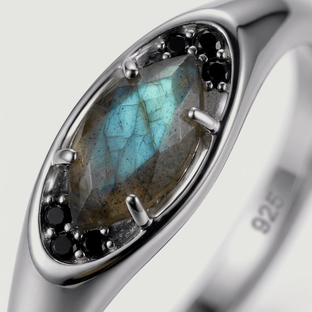 A close view reveals teal flashes and natural inclusions in a marquise labradorite held by silver prongs.
