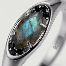 A close view reveals teal flashes and natural inclusions in a marquise labradorite held by silver prongs.