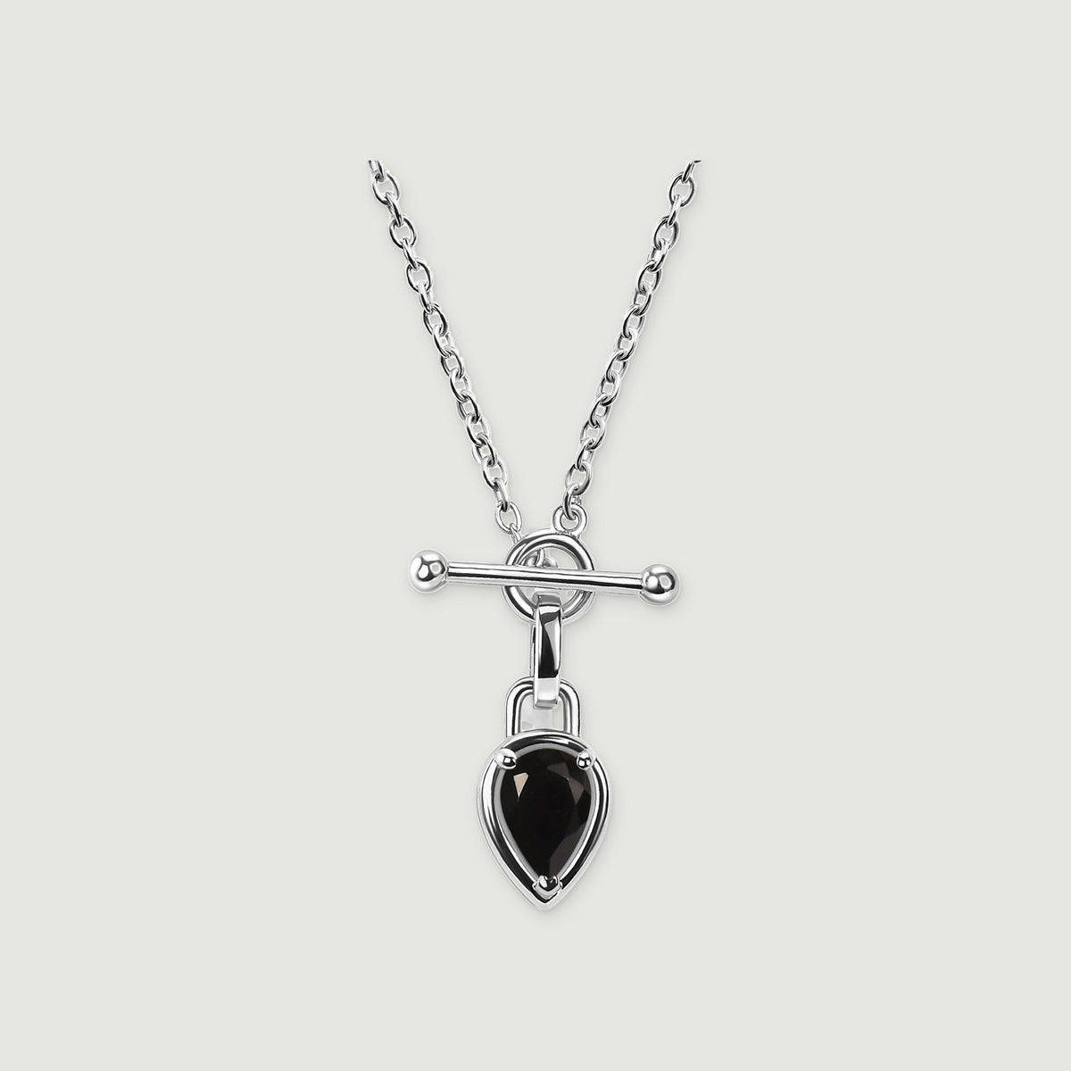 A bright silver-tone necklace shows a round clasp beneath a polished bar and a dangling black pear-shaped pendant.
