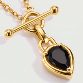 A close view shows the gold-tone prongs, faceted black stone, polished connector, and ball-ended bar clasp.