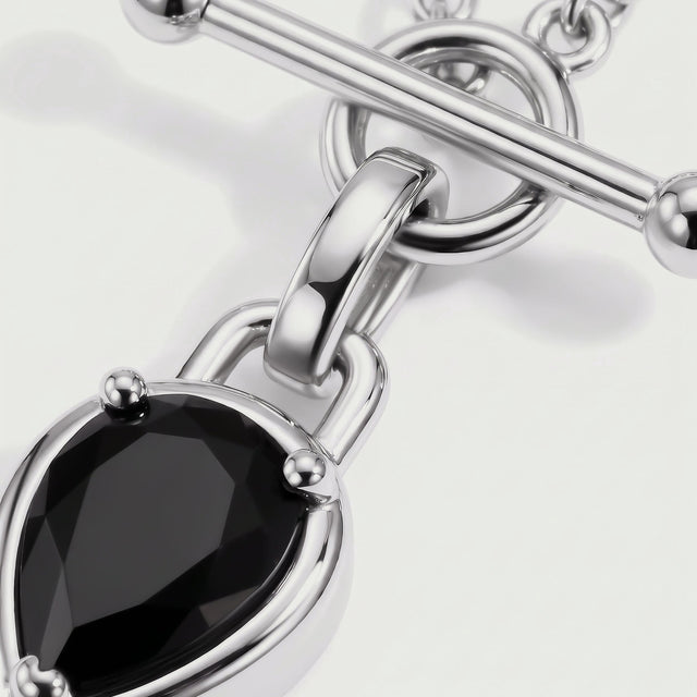 The black gemstone facets sit inside a reflective silver-tone setting beside a curved connector and circular clasp.