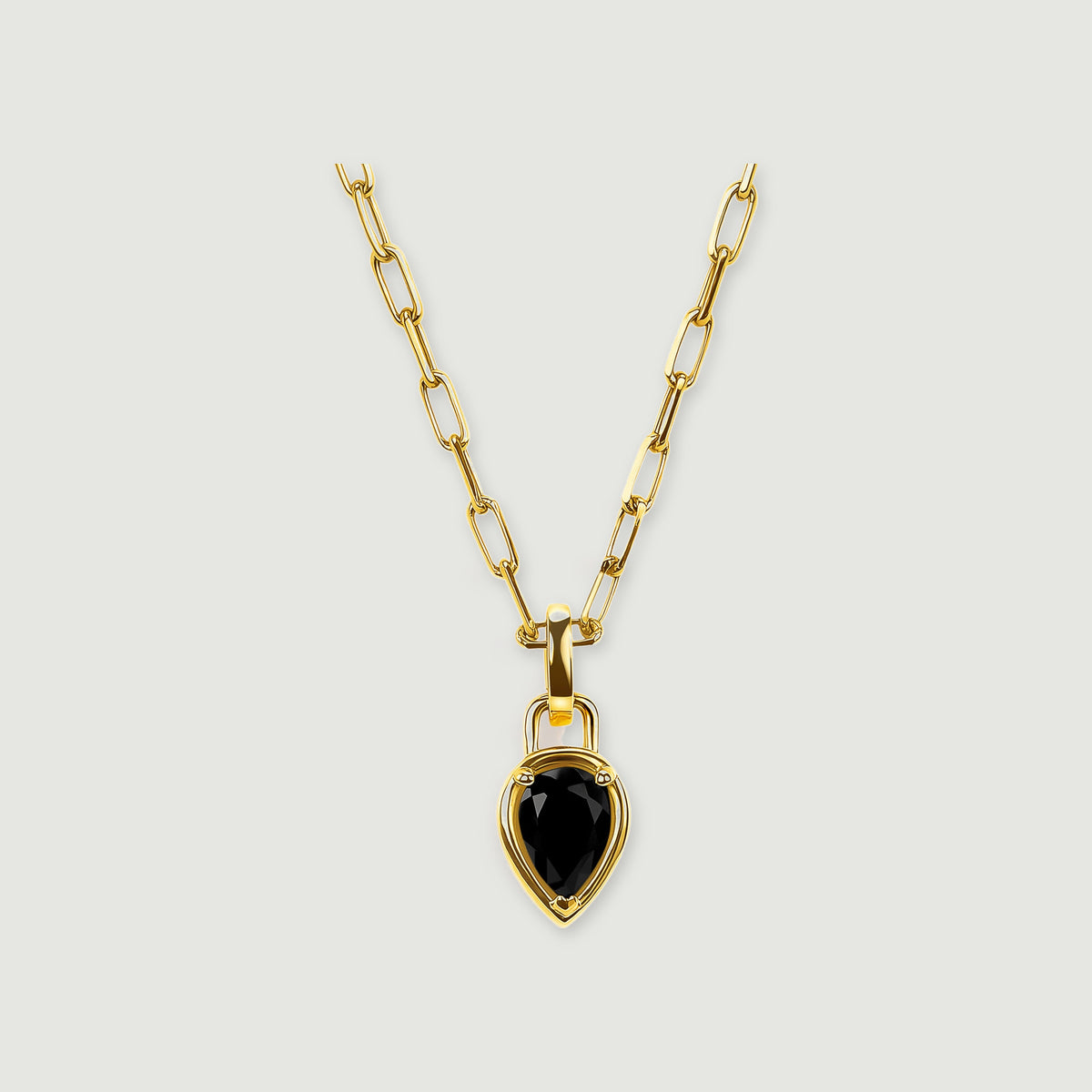 A yellow gold plated chain holds a pear-shaped black onyx pendant against a light gray background.
