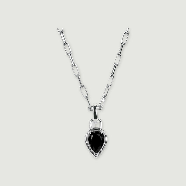 A silver-tone chain and pear-shaped black pendant are centered on a softly shadowed gray surface.