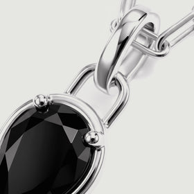 The polished silver-tone bail and rounded prongs frame a close-up of the black gemstone.