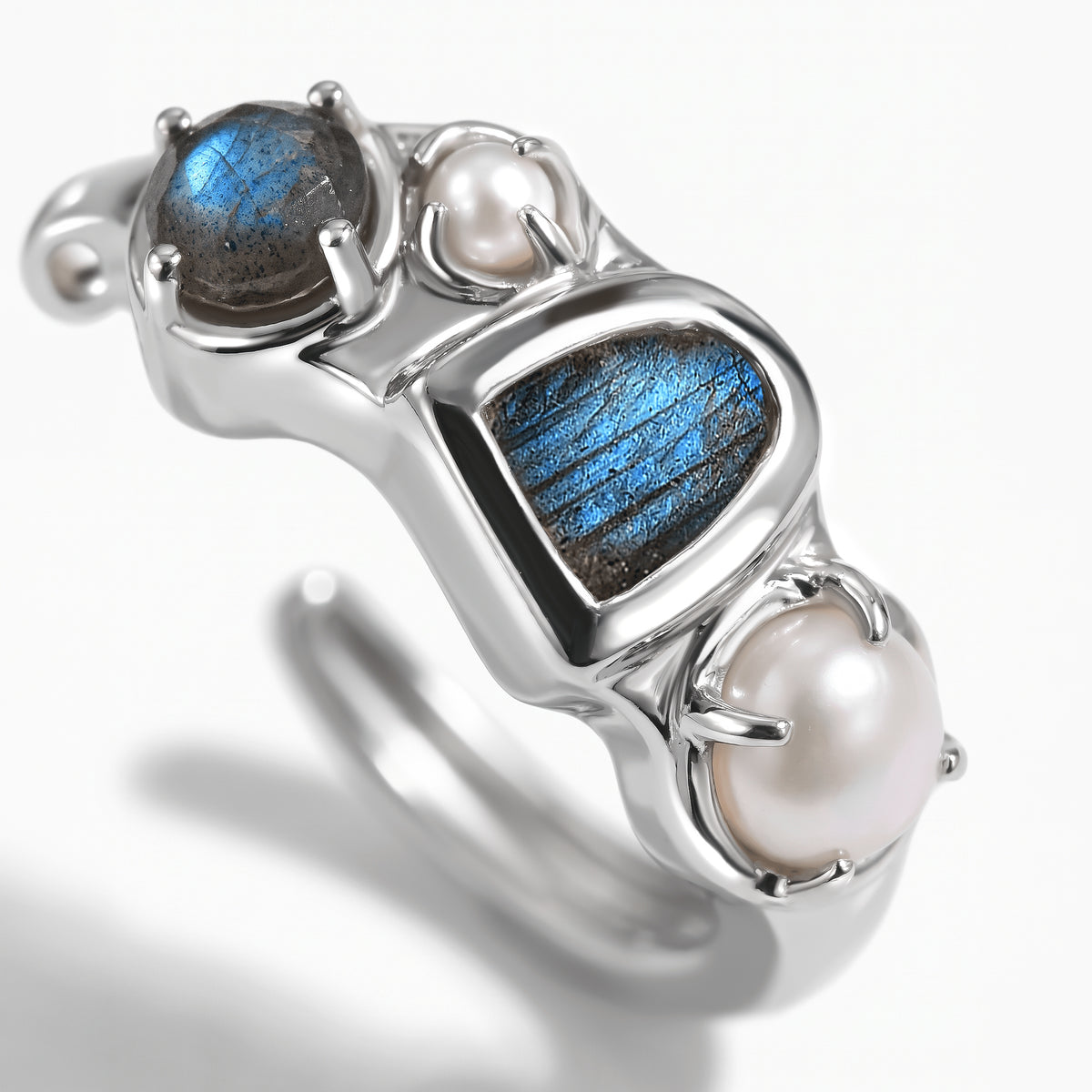 A close view shows the raw blue labradorite center, round upper stone and two pearls in a polished white rhodium hoop.