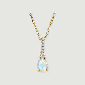 A yellow gold necklace has a pear-shaped moonstone beneath a vertical row of five clear stones on a light gray background.