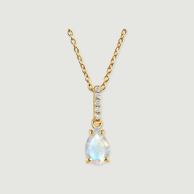 A yellow gold necklace has a pear-shaped moonstone beneath a vertical row of five clear stones on a light gray background.