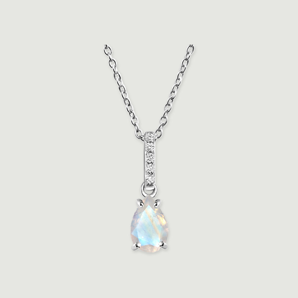 A silver chain supports a pale blue pear-shaped moonstone and a slim stone-set bail against light gray.