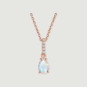 A rose gold chain and four rounded prongs frame an iridescent pear-shaped moonstone on a soft gray surface.