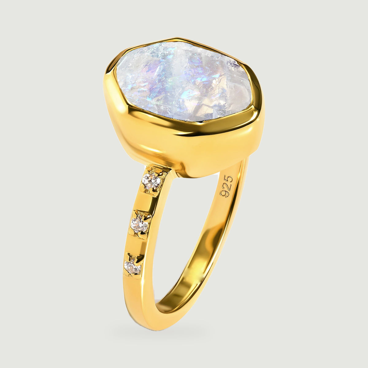 The side of a yellow gold ring reveals the raised moonstone bezel and three clear stones on the shoulder.