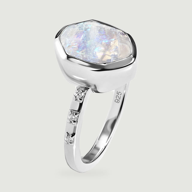 An upright silver ring shows the textured moonstone surface, deep bezel, and narrow stone-set band.