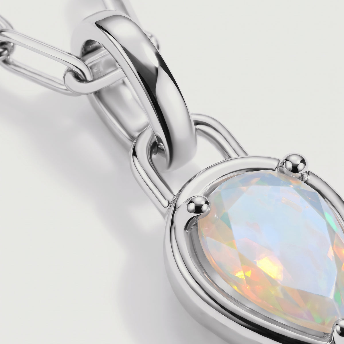 The silver-tone pendant setting and curved connector frame a faceted opal in close detail.