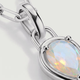 The silver-tone pendant setting and curved connector frame a faceted opal in close detail.