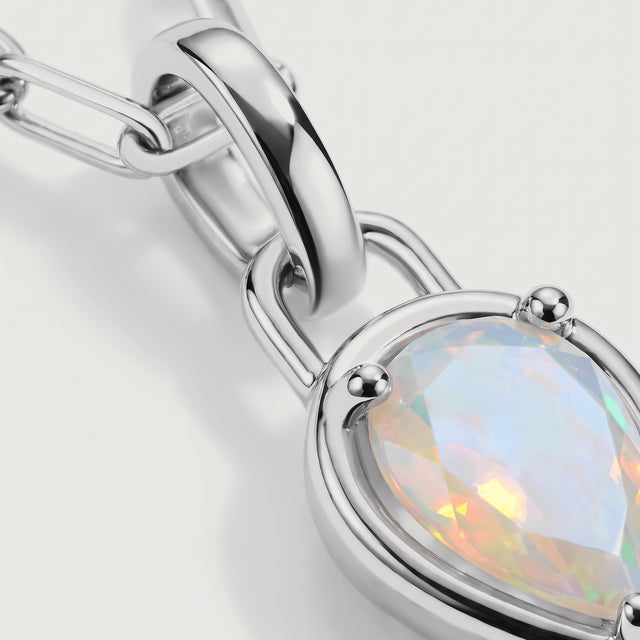 The silver-tone pendant setting and curved connector frame a faceted opal in close detail.