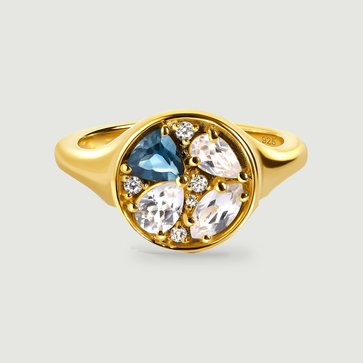 A yellow gold ring displays a round face with one blue stone and three clear pear-shaped stones.