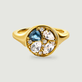 A yellow gold ring displays a round face with one blue stone and three clear pear-shaped stones.