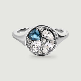 A sterling silver ring shows a blue stone and clear faceted stones within a polished circular face.