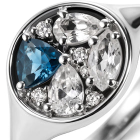 The blue and clear faceted stones sit inside the bright rim of the silver ring.