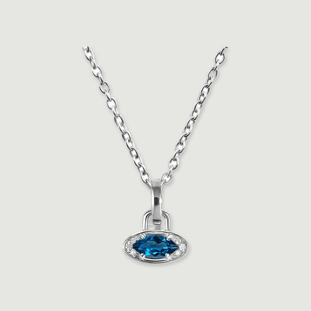 A white rhodium plated chain holds a horizontal blue topaz charm against a light gray background.
