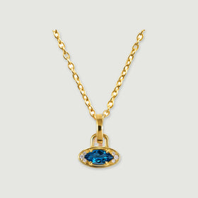 A yellow gold plated chain holds a horizontal blue topaz charm against a light gray background.
