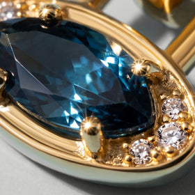 Blue topaz facets and a row of clear accent stones fill this close view of the yellow gold plated setting.