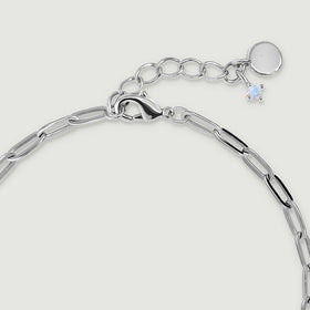 A white rhodium plated lobster clasp sits beside round extension links, a plain round tag, and a small pale charm.