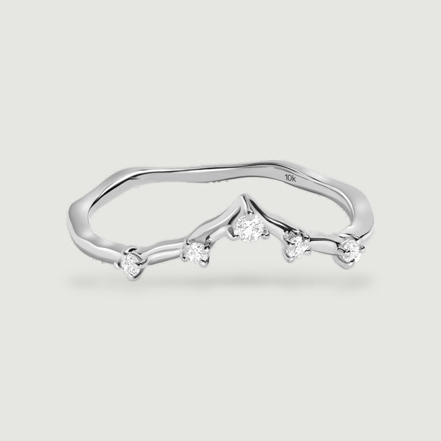 A white gold diamond ring is shown from a low front angle with its slender band and raised central point visible.