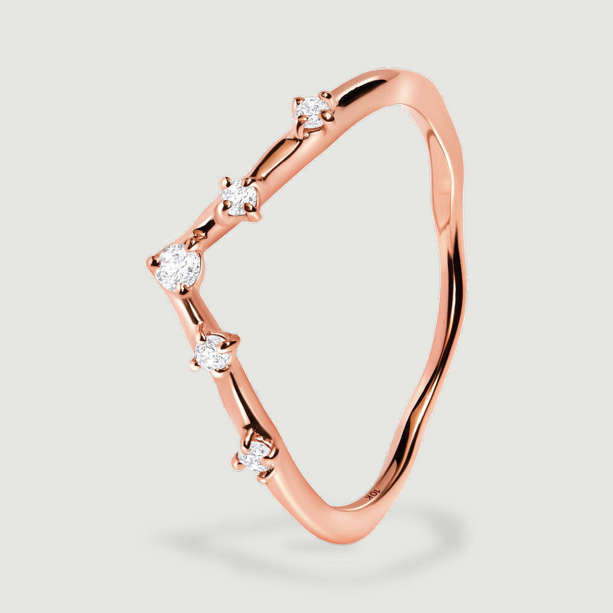 The rose gold ring stands at an angle, showing its diamond prongs and the polished inner band.