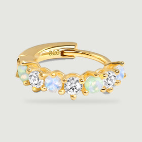 A yellow gold hoop lies flat with its hinged back and row of colored and clear stones facing forward.