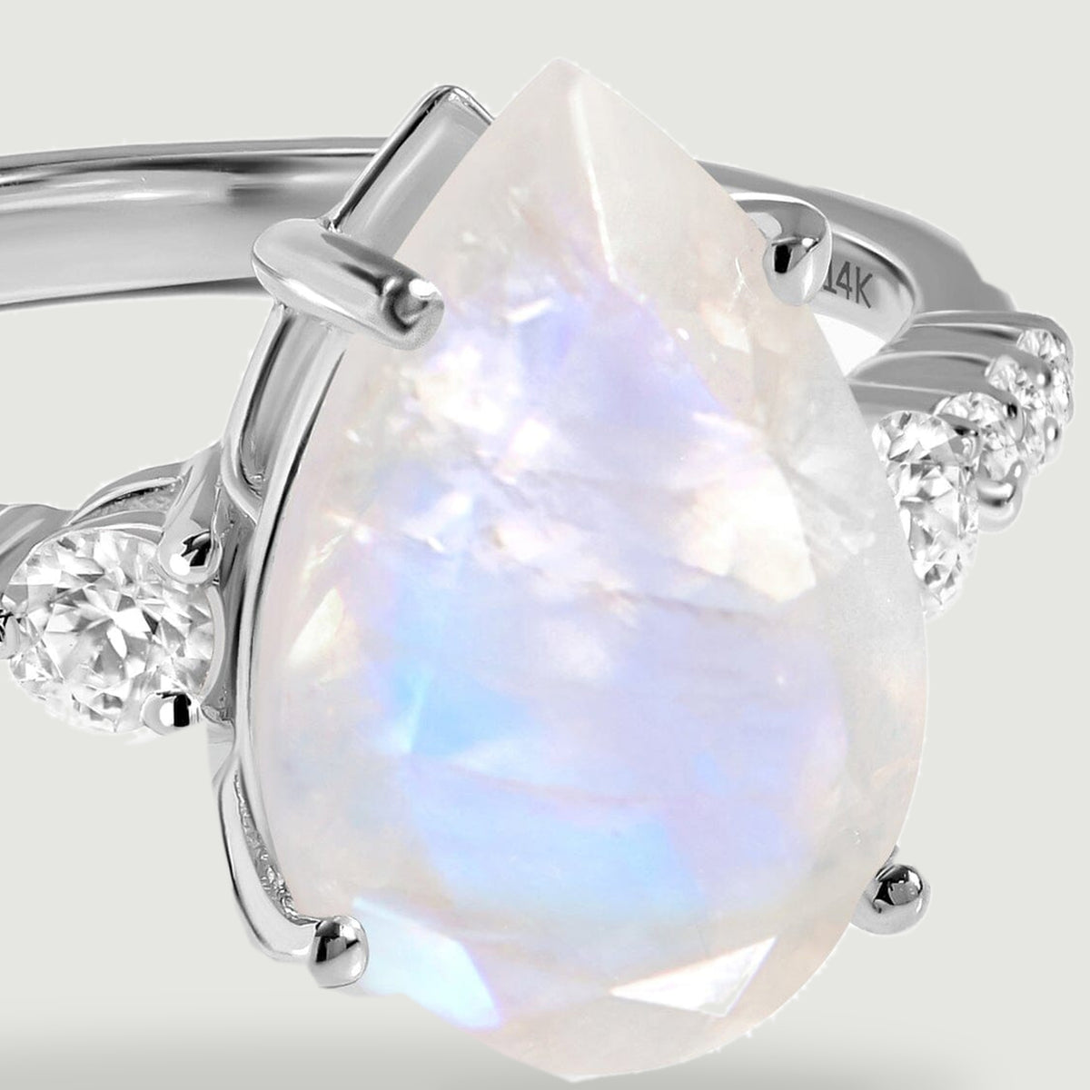 A close view shows the faceted moonstone, white gold prongs, and round diamonds along the ring shoulders.