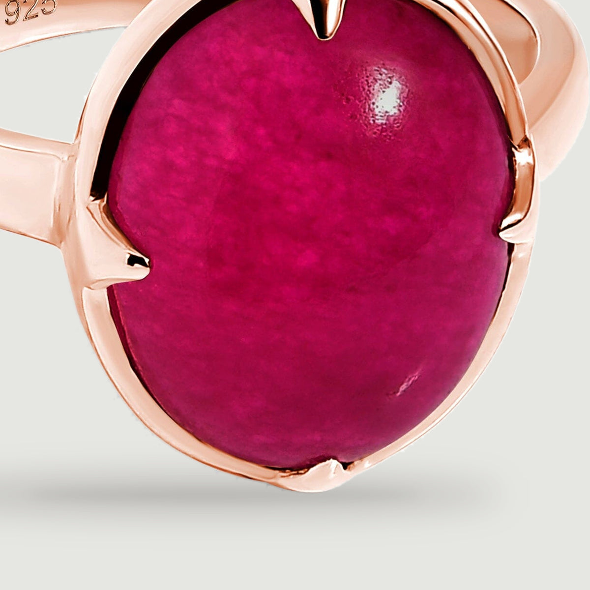 A close view shows the oval pink stone, pointed rose-gold prongs, and reflective rim.