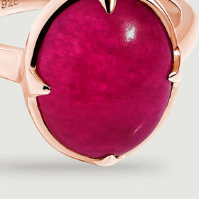 A close view shows the oval pink stone, pointed rose-gold prongs, and reflective rim.