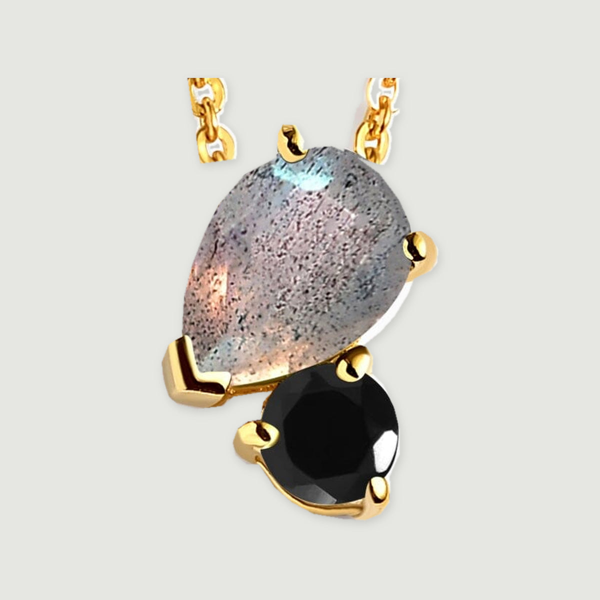 Yellow gold prongs frame the speckled gray pear-shaped stone above a faceted black round stone in this close-up.