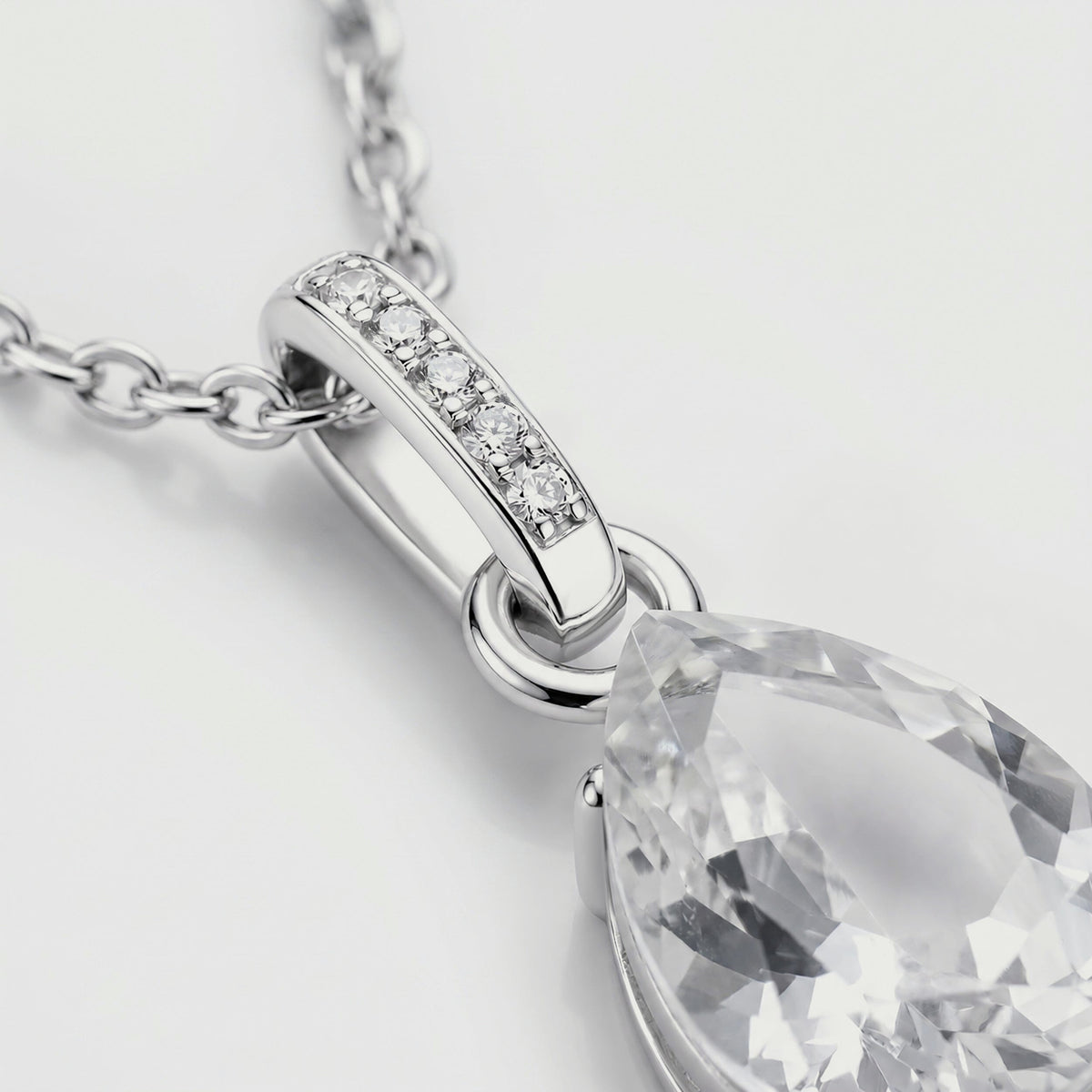 A close view shows five round stones in the silver bail beside the clear pendant and polished connecting ring.