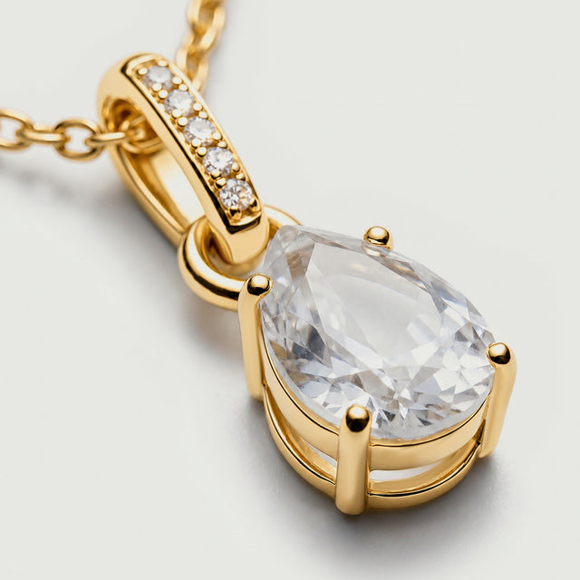 An angled close-up shows gold prongs and the open side of the setting beneath a clear faceted stone.